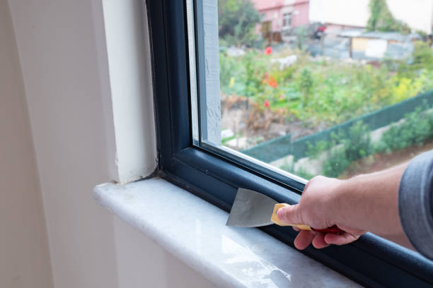 istock The man is using a putty knife to clean the old insulation from the windowsill. 1800448265