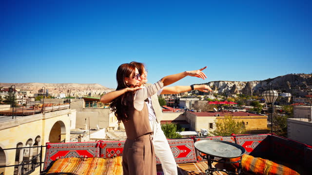 female tourist couple share their excitement by dancing on their vacation at rooftop patio of hotel