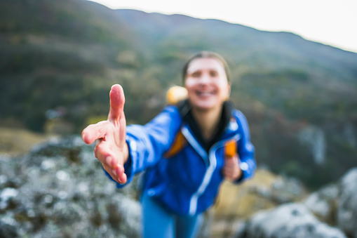 Young hiker woman reaching for someone's hand on a hiking trail