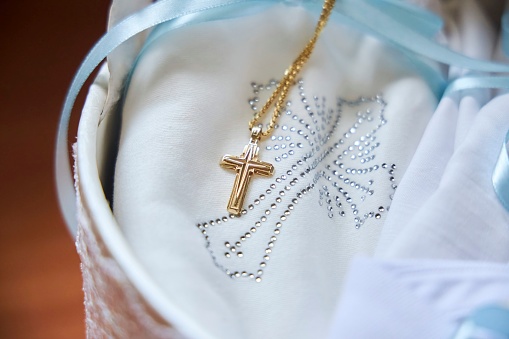 The Christian Orthodox cross lies on the baptismal clothes for the child. Christian traditions.