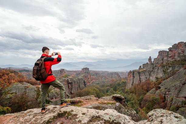 istock Young hiker using phone at the mountain peak 1800498656