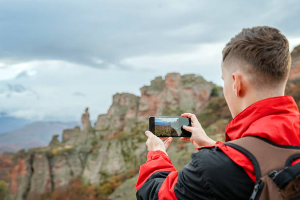 istock Young hiker using phone at the mountain peak 1800499194