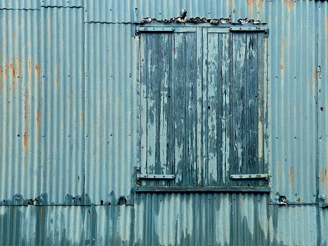 Old wooden shutters on a weathered corrugated building in Great Yarmouth. November 2023