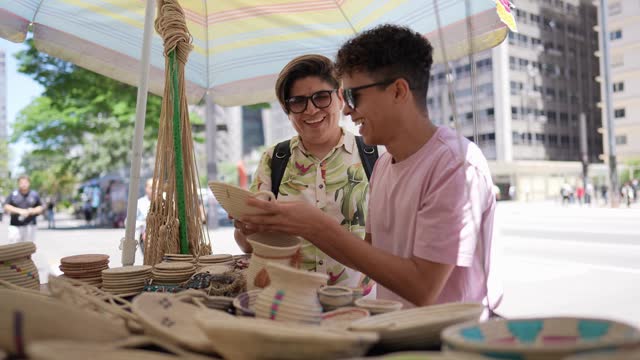 Tourist gay couple buying craft products at a street market