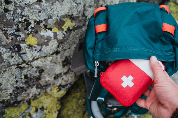 istock Hand taking out first aid kit from hiking backpack, red first aid kit on a journey, concept of an autonomous hike in the forest. 1800612106