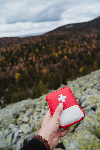 First aid kit in a man's hand against the background of mountains, a small camping first aid kit, a cosmetic bag with medicines. High quality photo