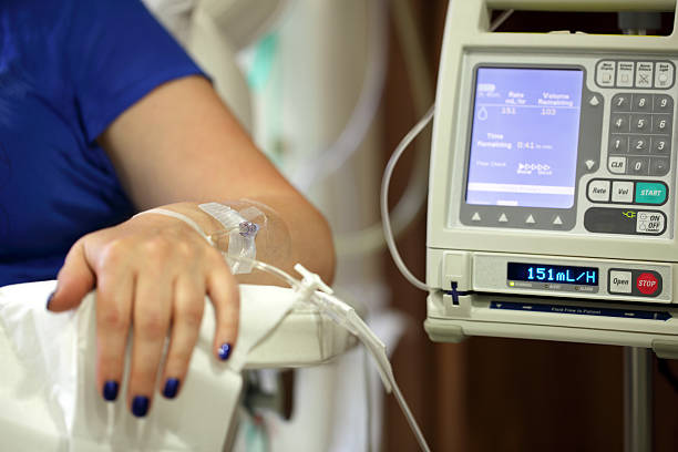 Intravenous IV drip Infusion pump feeding IV drip into patients arm focus on needle chemotherapy drug stock pictures, royalty-free photos & images