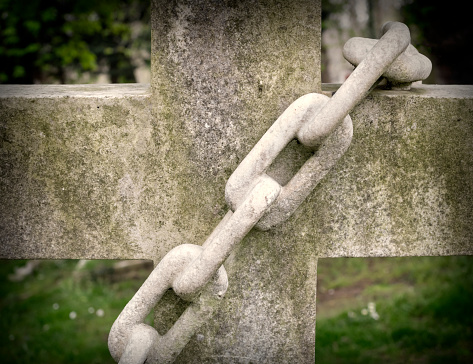 A reconstituted stone chain on a graveyard cross in a cemetery.