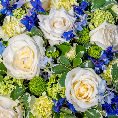 A delicate floral funeral tribute containing roses at a cemetery.