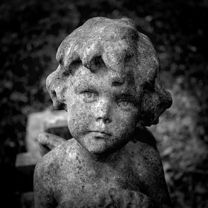 A thoughtful, sad little Victorian stone cherub in the children’s plot of a suburban cemetery.