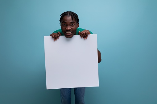 smiling funny african young man holding billboard with mockup.