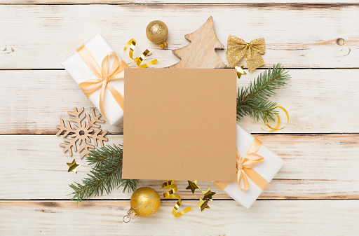 Greeting card mockup with christmas decor on wooden background, top view