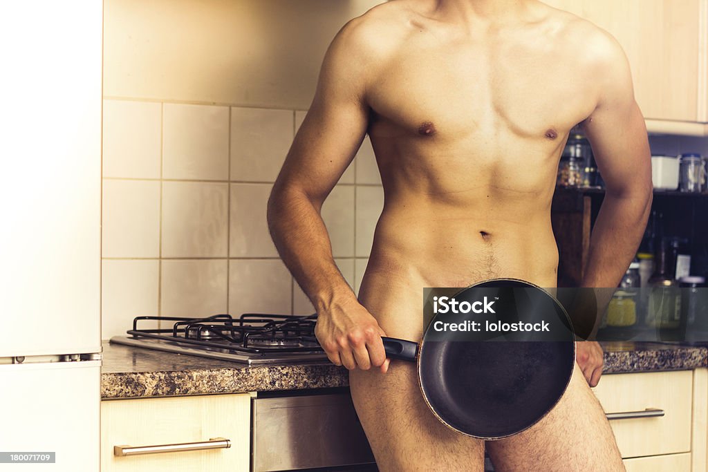 Naked chef de pie junto a la cocina con sartén - Foto de stock de Desnudo libre de derechos