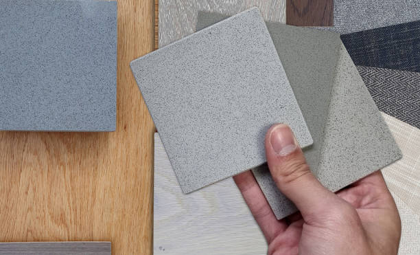 istock designer holds quartz samples palette to compares with wooden engineering flooring tiles, stone and concrete tiles, fabric laminated. mood board shows various type of material samples, close up view. 1800721348