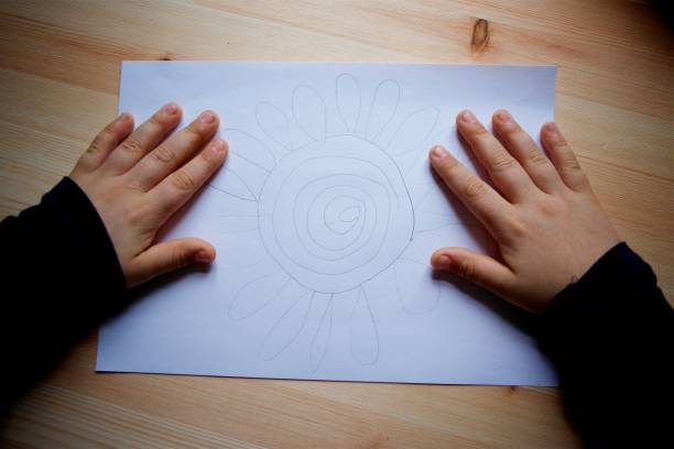 istock Children's hand and drawing on white paper with a simple pencil. 1800727703