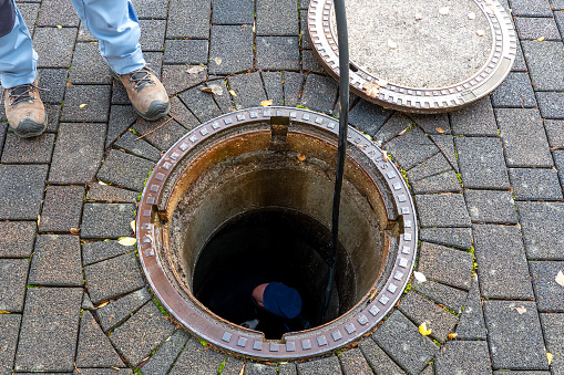 Blocked pipe. Sewer inspection with camera. Sewer cleaning company worker at work in a manhole