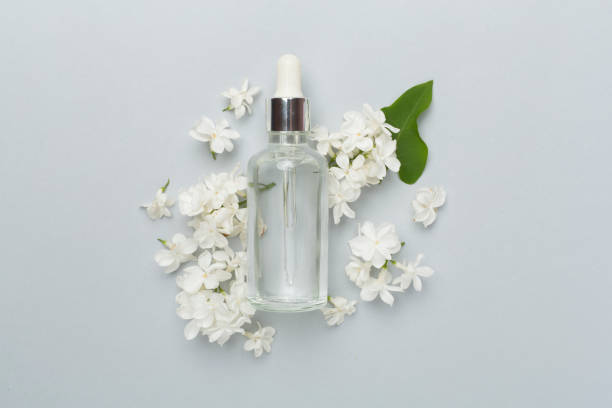 istock Face serum with flowers on color background, top view 1800730393
