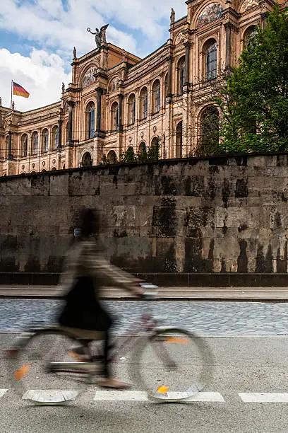 A young woman rides past the impressive facade of the Maximilianeum, a building of the Bavarian state parliament.