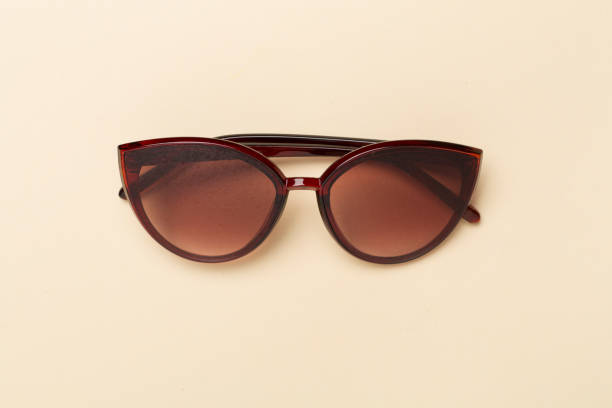 Sunglasses on color background, top view.
