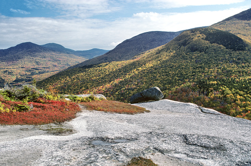 Spectacular view of mountains and national forest from granite ledge atop summit of Middle Sugarloaf Mountain in the White Mountains of New Hampshire.