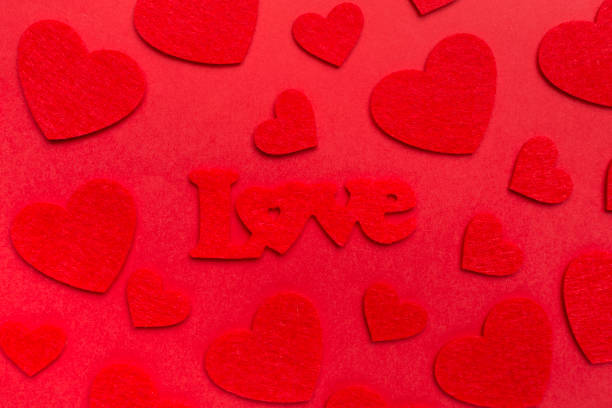 Felt word love with hearts on color background, top view