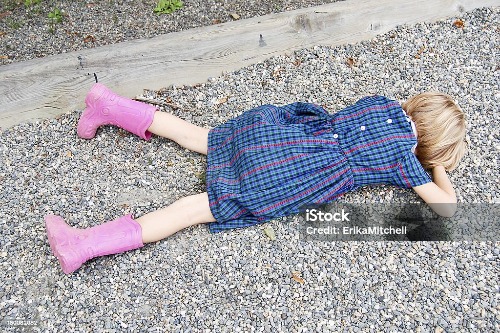 Sad girl lying on the ground A sad child lies on the gravel of a school playground. Tantrum Stock Photo