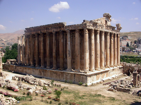 Discover the grandeur of Bacchus Temple in Baalbek, an imperial relic nestled within the Beqaa Valley of Lebanon. Towering pillars, intricate carvings, and scattered ruins intertwine amidst nature's embrace beneath azure skies and distant hills.