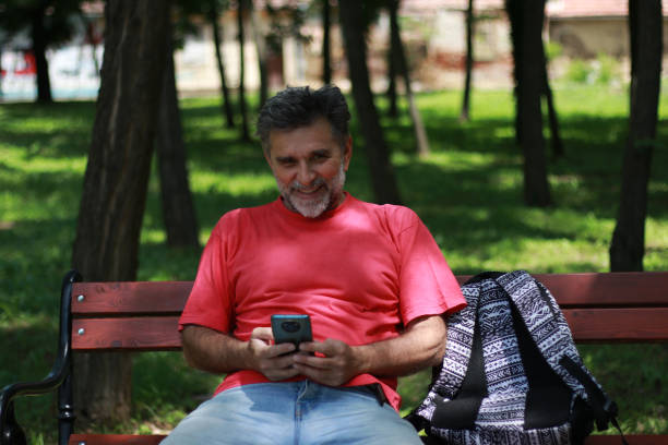 istock Senior bearded man relaxing on bench in public park 1800842421