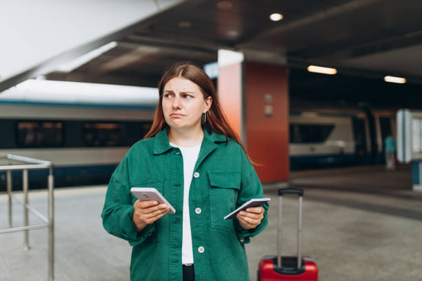 istock Young refugee redhhead woman crying and waiting train on station platform, she lost and using smart phone. Railroad transport concept 1800920937