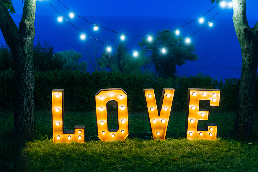 The inscription is love. Glowing large letters. Wedding decorations outdoors.