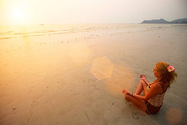istock Young woman practicing yoga on the beach at sunset 180098752
