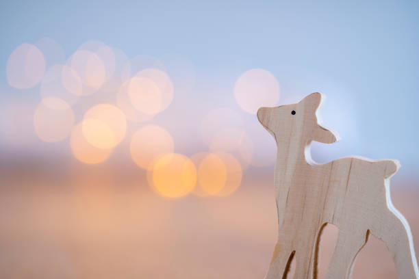 atmospheric blue and purple Christmas greetings card with a wooden deer figure in the foreground and bokeh effects in the background