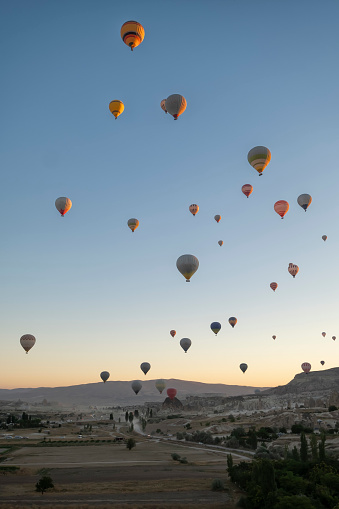 numerous hot air balloons flying over the fairy chimneys, at the Goreme airfield at dawn, Cappadocia, Turkey, vertical
