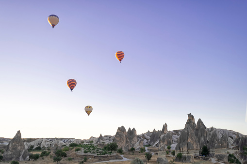 hot air balloons flying over the fairy chimneys, at the Goreme airfield at dawn, Cappadocia, Red Valley, Turkey, Goreme National Park, horizontal