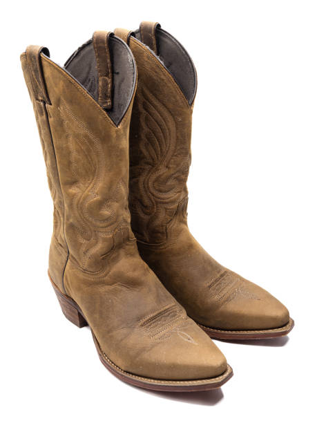 istock A pair of light brown cowboy boots with stiched patterns against white background seen from the side and above. 1801131734