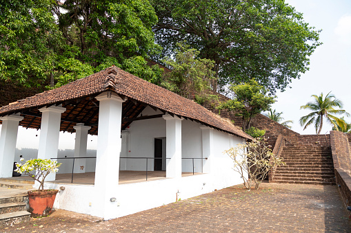 This image showcases the Reis Magos Fort, a historical landmark located along the banks of the Mandovi River in Goa. The fort, known for its distinctive red-laterite walls and rugged architecture, stands as a testament to Goa's rich colonial past. In the photograph, the fort's imposing structure is captured against the backdrop of the lush Goan landscape and the expansive river. The image aims to convey the historical significance of the Reis Magos Fort, highlighting its role as a defensive stronghold and a cultural heritage site. It offers viewers a glimpse into the architectural splendour and strategic importance of this well-preserved fort, making it a captivating subject for those interested in the history and architecture of Goa.