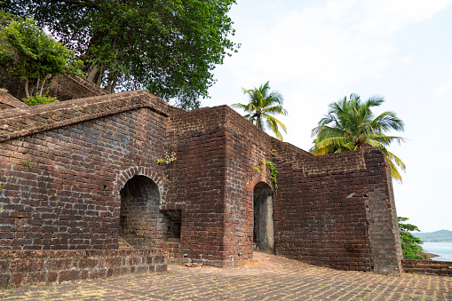 This image showcases the Reis Magos Fort, a historical landmark located along the banks of the Mandovi River in Goa. The fort, known for its distinctive red-laterite walls and rugged architecture, stands as a testament to Goa's rich colonial past. In the photograph, the fort's imposing structure is captured against the backdrop of the lush Goan landscape and the expansive river. The image aims to convey the historical significance of the Reis Magos Fort, highlighting its role as a defensive stronghold and a cultural heritage site. It offers viewers a glimpse into the architectural splendour and strategic importance of this well-preserved fort, making it a captivating subject for those interested in the history and architecture of Goa.