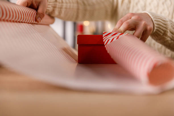 istock Man wrapping a little red gift box in a wrapping paper 1801202264