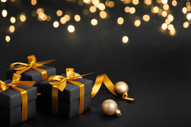 istock Black gift box with golden ribbon bow on black background 1801285481