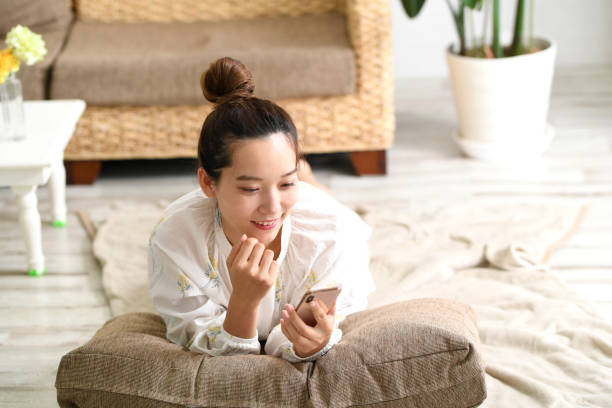 istock A young Asian woman in pajamas is lying down and smiling while using a smartphone 1801293720