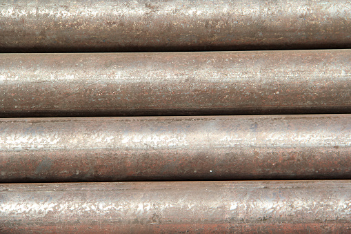 Rusting section of a gray metal pipe on a sunny morning.
