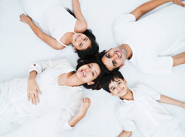 Happy family lying on the bed High angle view of a happy family lying on the bed happy indian young family couple stock pictures, royalty-free photos & images