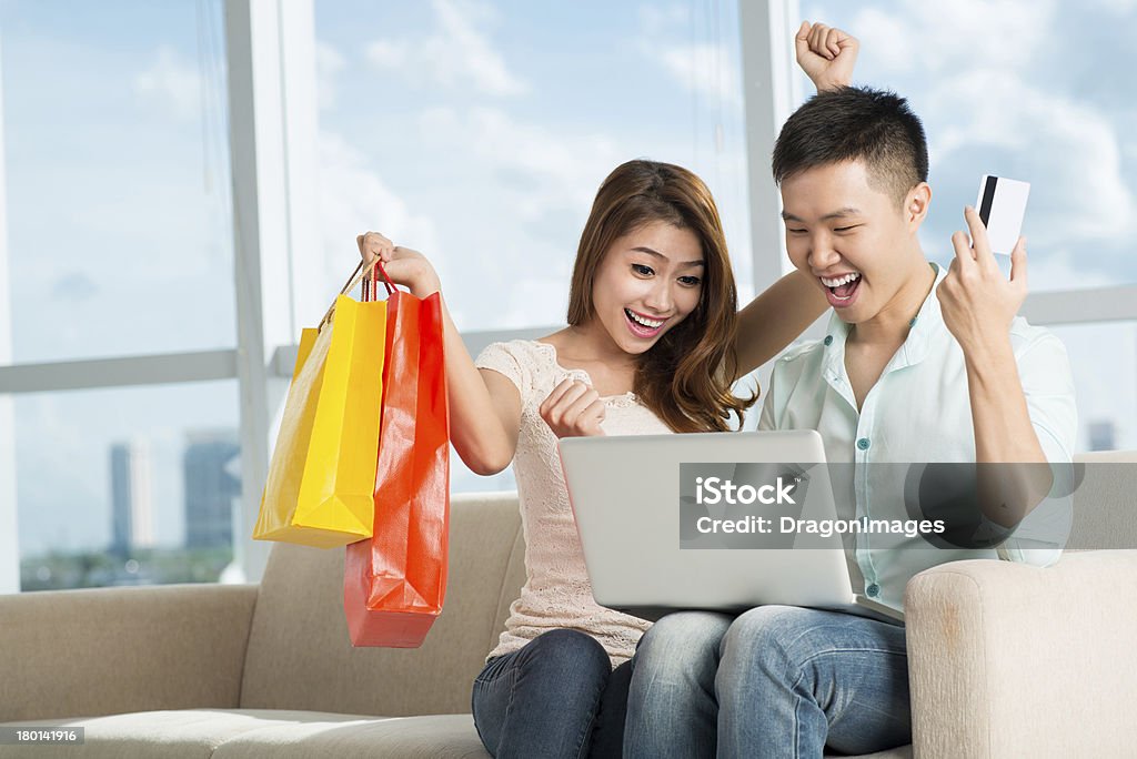 Excitement of shopping A young excited couple buying something using Internet at home Adult Stock Photo