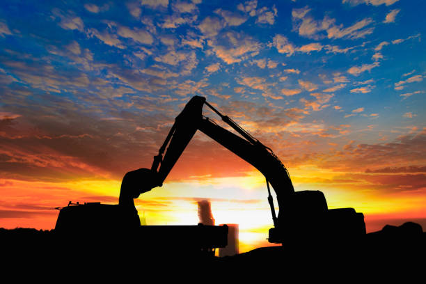 Crawler excavators silhouette are digging the soil in the construction site. on the sky  and  sunset background