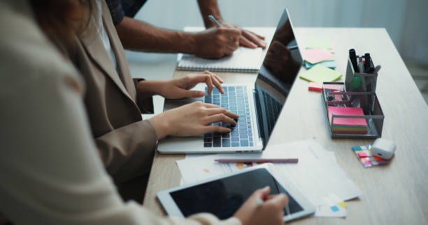 istock Group of diverse business people using a laptop while working together in a modern workspace 1801440917