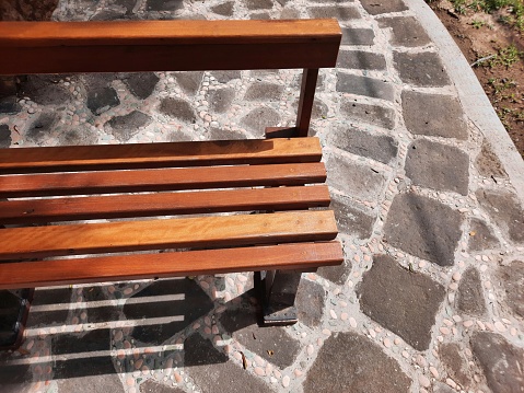 Wooden chair on the park under the trees. Object close up outdoor garden. Background template copy space.