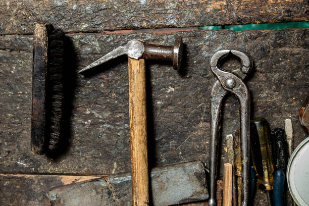 A shoemaker with a long career repairing shoes, changes soles, mends and places insoles on behalf of his clients, in an establishment with widely used tools and where he has been working for many years.
