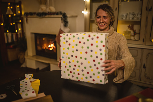 Woman wrapping gifts for Christmas at home.