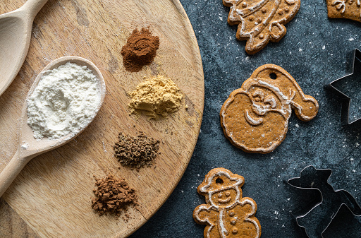 Holiday Season winter flat lay background. Seasonal baking ingredients top view. Christmas baking composition, with gingerbread cookies, flour, spices and cookie cutters.