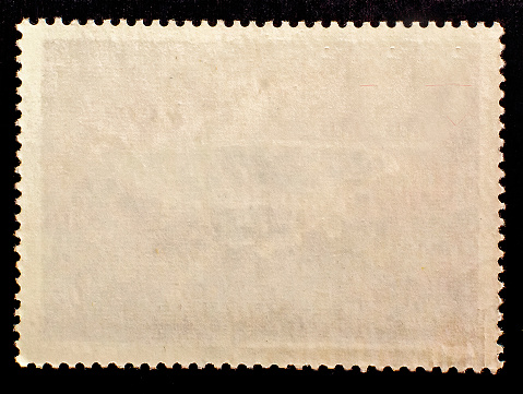 Blank rectangle postage stamp  isolated on black background. Texture of old paper